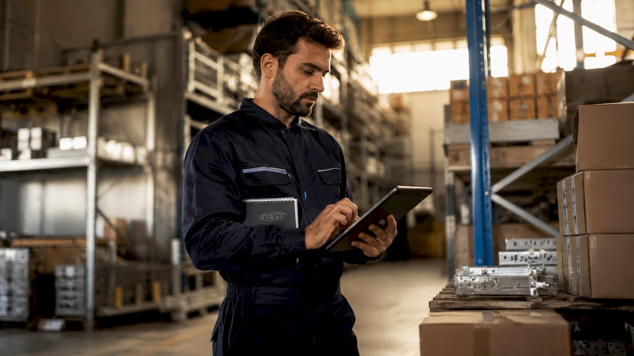 Dita che digitano su una tastiera industriale posizionata accanto a un armadietto digitale