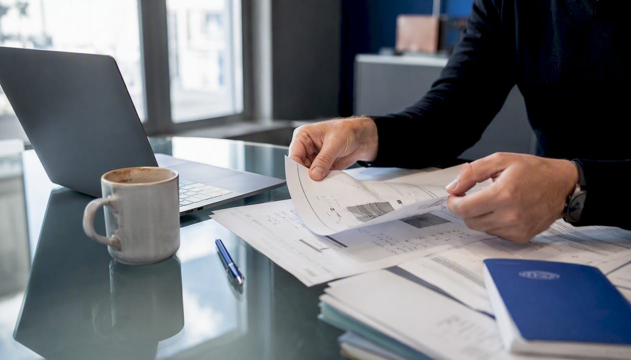 Mani che sistemano e classificano documenti di certificazione sul tavolo