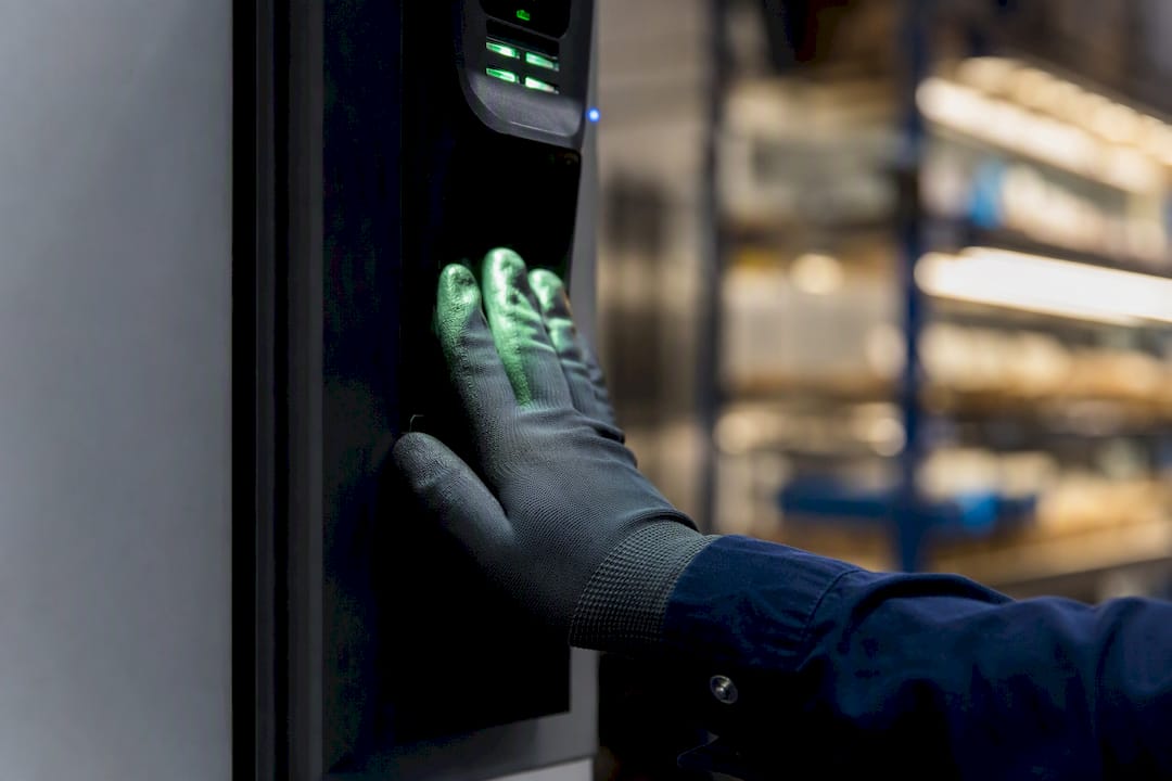 Mano guantata vicino a un lettore di vene della mano in fabbrica