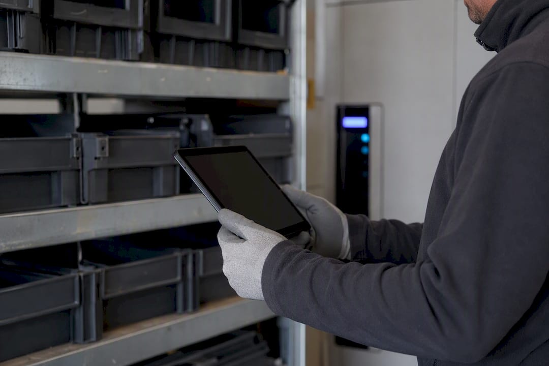 Mani che tengono un tablet vicino a scaffali di armadietti intelligenti